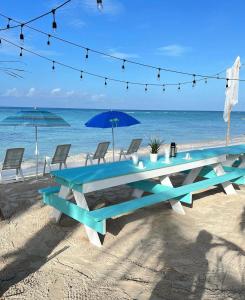 a picnic table on the beach with a blue umbrella at Casa rosada beach front in Mano Juan