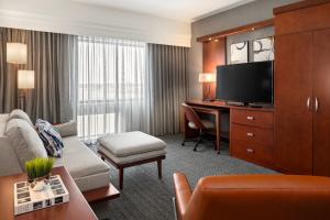 a hotel room with a couch and a desk with a television at Courtyard Mankato Hotel & Event Center in Mankato