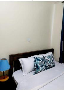 a bed with a blue lamp and a blue pillow at Rubi Apartment in Naivasha