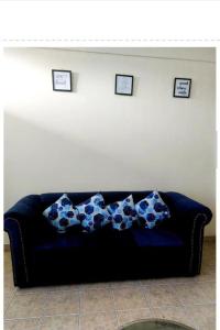 a blue couch in a living room with three pictures on the wall at Rubi Apartment in Naivasha