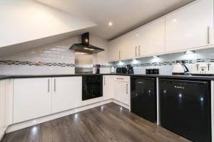 uma cozinha com armários brancos e electrodomésticos pretos em The Mayfield Seamer em Scarborough