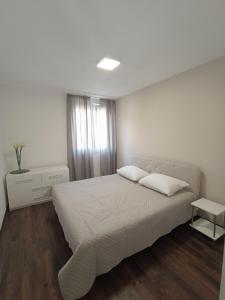 ein weißes Schlafzimmer mit einem Bett und einem Fenster in der Unterkunft Apartman A&D in Ljubuški