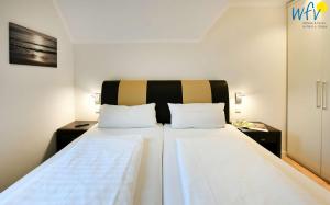 a bedroom with a large bed with two pillows at Bootshaus in den Duenen - 5 - "Ferienwohnung Strandgut" in Wangerooge