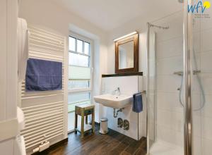 a white bathroom with a sink and a shower at Bootshaus in den Duenen - 5 - "Ferienwohnung Strandgut" in Wangerooge