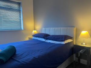 a bedroom with a bed with blue sheets and two lamps at Campion lodge in Hull