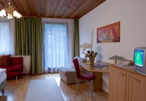 ein Wohnzimmer mit einem Schreibtisch, einem Sofa und einem TV in der Unterkunft Gasthof Pichler in Bruck an der Mur
