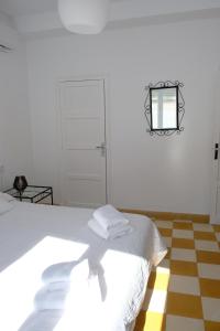 a white room with a bed and a mirror on the wall at Casa de la Corredera in Arcos de la Frontera