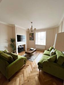 a living room with two green couches and a table at Cottage in Pembroke, Close to beaches in Pembrokeshire