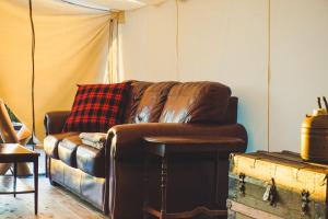 a living room with a brown leather couch and a table at Fronterra Farm- Luxury Camp Experiences in Hillier