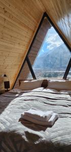 a bed in a room with a large window at Hill silence in Kazbegi