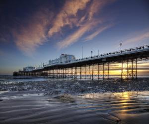 a pier on the beach at sunset with the water at Garden View in Worthing