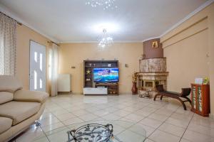 a living room with a tv and a couch and a fireplace at Villa George in Nea Peramos