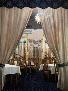 een eetkamer met tafels, stoelen en gordijnen bij Готель МАГНАТ 
