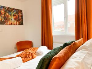 a bedroom with a bed with an orange curtain and a window at Antley House in Andover