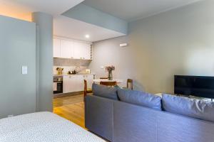 a living room with a blue couch and a kitchen at Charming Studio in central Lisbon in Lisbon