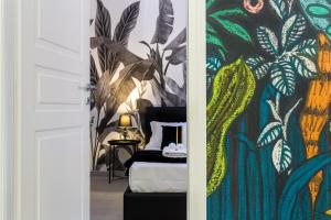 ein Schlafzimmer mit einem Bett und einem Wandbild von Pflanzen in der Unterkunft Tropical - Boutique Apartment in Gallipoli