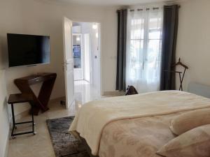 sypialnia z łóżkiem i telewizorem z płaskim ekranem w obiekcie Elégant-Cosy 2P55M2 dans bas de villa provençale ! w mieście Villeneuve-Loubet