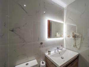 a white bathroom with a sink and a mirror at Pandora's Corfu Apartments in Agios Gordios