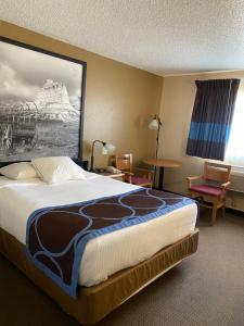 オガララにあるSuper 8 by Wyndham Ogallalaの大きなベッドとテーブルが備わるホテルルームです。