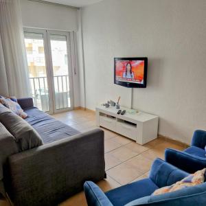 a living room with two couches and a tv on a wall at Casinhas da Praia in São Martinho do Porto