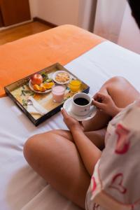 a woman sitting on a bed with a tray of food and a cup of coffee at Hotel Alma De Buenos Aires in Buenos Aires