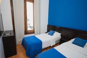 1 dormitorio con 2 camas y pared azul en Hotel Alma De Buenos Aires en Buenos Aires