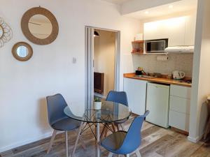 Una cocina y un comedor con una mesa de cristal y sillas. en Casa de los Loles Tandil, en Tandil