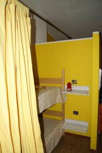 a room with two bunk beds with a yellow wall at BILOCALE CON VISTA MARE E MON in Cala Gonone