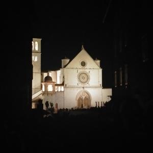 una grande chiesa bianca con una torre dell'orologio di notte di Appartamenti Santa Chiara ad Assisi