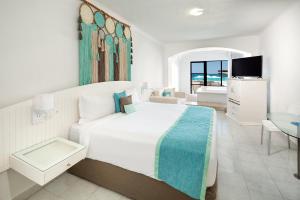 a white bedroom with a large bed and a television at Cyan Cancun Resort & Spa in Cancún