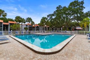 Una piscina en un resort con sillas y árboles. en Midnight Cove 6327 #725, en Sarasota