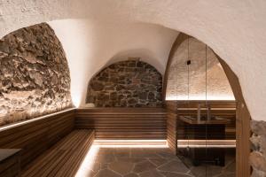 a spa room with a stone wall and a bench at Leuchtenburg am See in Caldaro