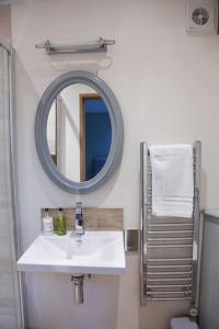 uma casa de banho com um lavatório branco e um espelho. em BARLEY - cosy stylish apartment - easy access to Bath and many nearby attractions em Box