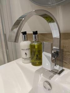 a bathroom sink with a faucet and two bottles of soap at BARLEY - cosy stylish apartment - easy access to Bath and many nearby attractions in Box