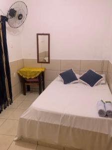 una camera da letto con un letto bianco con cuscini blu e uno specchio di Hotel Pousada AngraAntiga ad Angra dos Reis