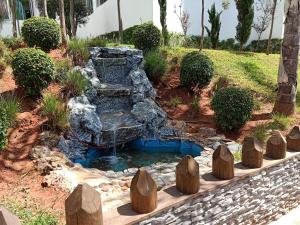 einen Wasserfall in einem Garten mit einem Steinbrunnen in der Unterkunft Appartement la Siesta beach resort Mohammedia in Mohammedia