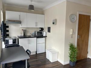 a small kitchen with white cabinets and a table at Amazing Studio Room in Walthamstoww in London