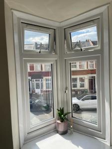 een kamer met drie ramen en een potplant bij Amazing Studio Room in Walthamstoww in Londen