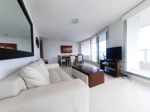a living room with a white couch and a television at Lujoso apartamento en la Mansa in Punta del Este