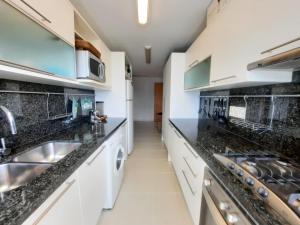a kitchen with white cabinets and black counter tops at Lujoso apartamento en la Mansa in Punta del Este