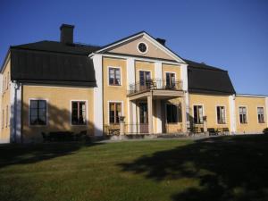 uma grande casa branca com um telhado preto em Thottska Villan em Strömsholm