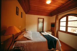 um quarto com uma cama com um candeeiro e uma janela em Hotel Geneve em Campos do Jordão