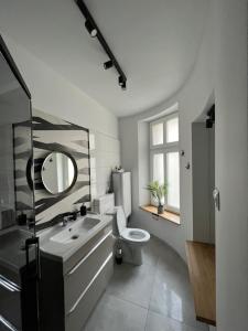a bathroom with a toilet and a sink and a mirror at Melody Apartment in Krakow