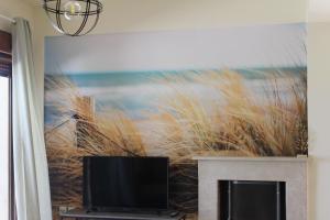 salon z telewizorem i obrazem plaży w obiekcie Petra w Áfitos