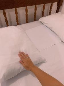 a person with their hand on a pillow on a bed at Hotel Pousada AngraAntiga in Angra dos Reis