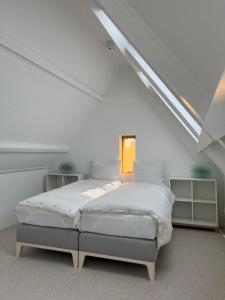 a white bedroom with a bed in a attic at Aventure in Noordwijk