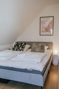 un letto con lenzuola e cuscini bianchi in una stanza di KEFS Guesthouse & Café a Ærøskøbing