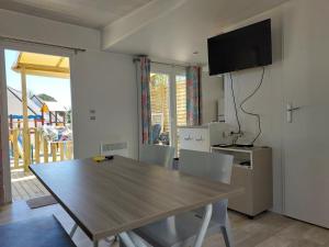a dining room with a table and a television at CARNAC Mobil-Home Camping 4 étoiles in Carnac