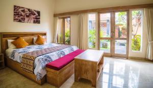 a bedroom with a bed and a table and windows at The Janan Villa in Sanur