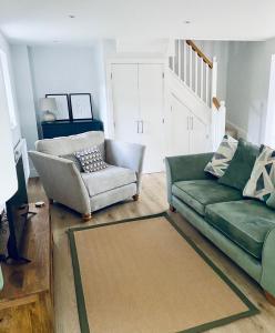 a living room with a green couch and a chair at Luxury Modern Cotswold Cottage in Stow on the Wold